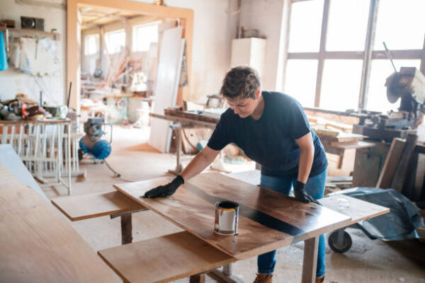 Female carpenter applying varnish on table surface