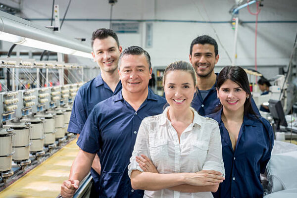 Group of people working at an embroidery factory and looking at the camera smiling